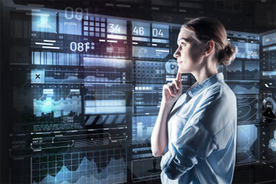 Looking interested. Clever experienced young programmer looking interested while standing in front of a futuristic device and thoughtfully touching her face