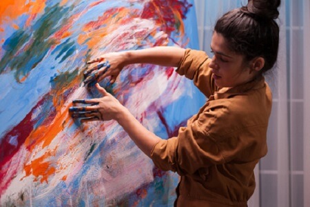 mujer pintando un cuadro con las manos