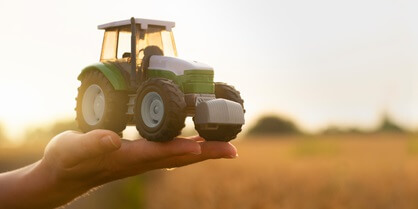 mano de agricultora sosteniendo un tractor de juguete