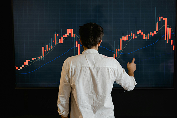 persona de espaldas en una pizarra con una gráfica naranja para asesoramiento financiero