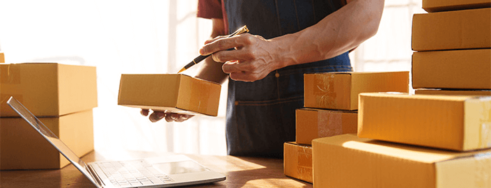 Imagen de un hombre con un paquete en la mano, escribiendo en él con un bolígrafo