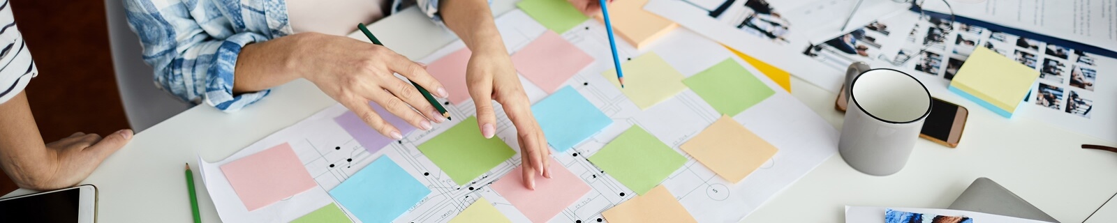 Manos sobre un papel lleno de post-it de colores