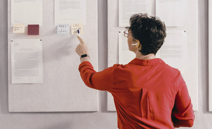persona de espaldas señalando un postit con camisa roja para consultoría para pymes