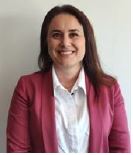 Retrato profesional de una persona con chaqueta rosa y camisa blanca, sentada frente a un fondo claro. Imagen sencilla, bien iluminada y con enfoque corporativo.