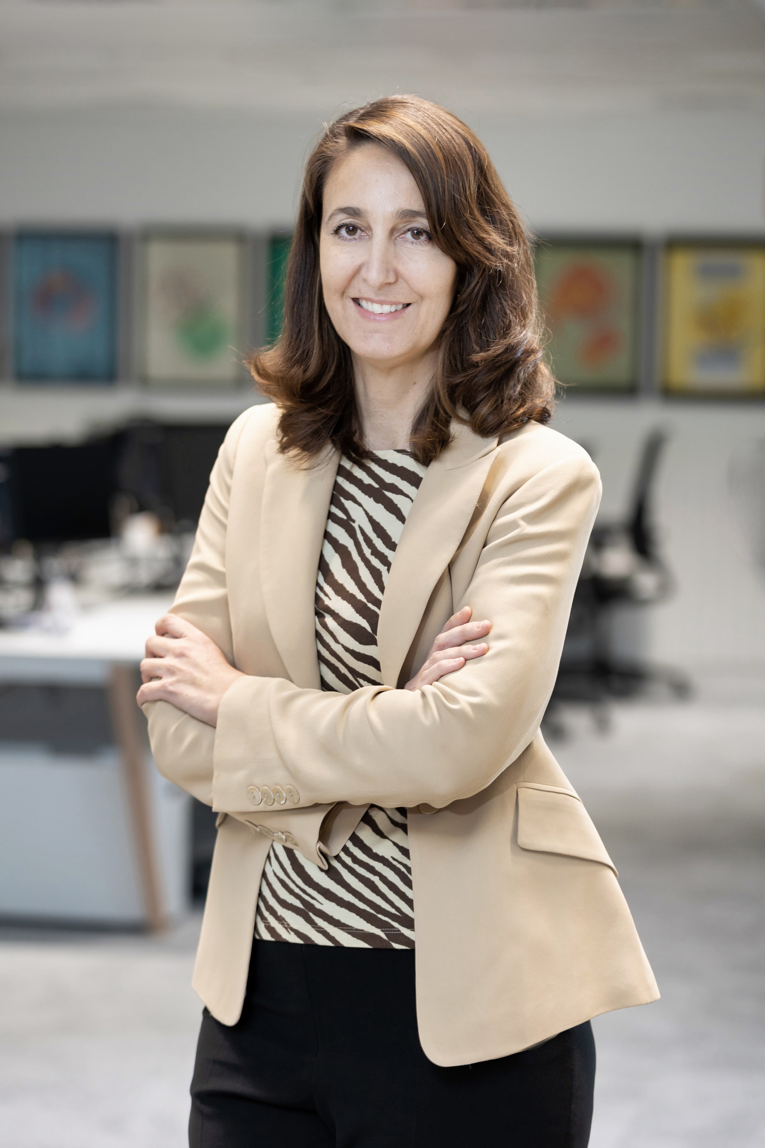 persona con el pelo largo y los brazos cruzados con una americana beige y una camisa de rayas marrones