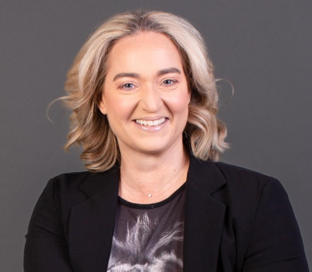 persona con pelo media melena rubia sonriente con chaqueta negra