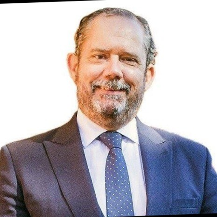 Primer plano de una persona son barba sonriendo con traje y corbata de color azul