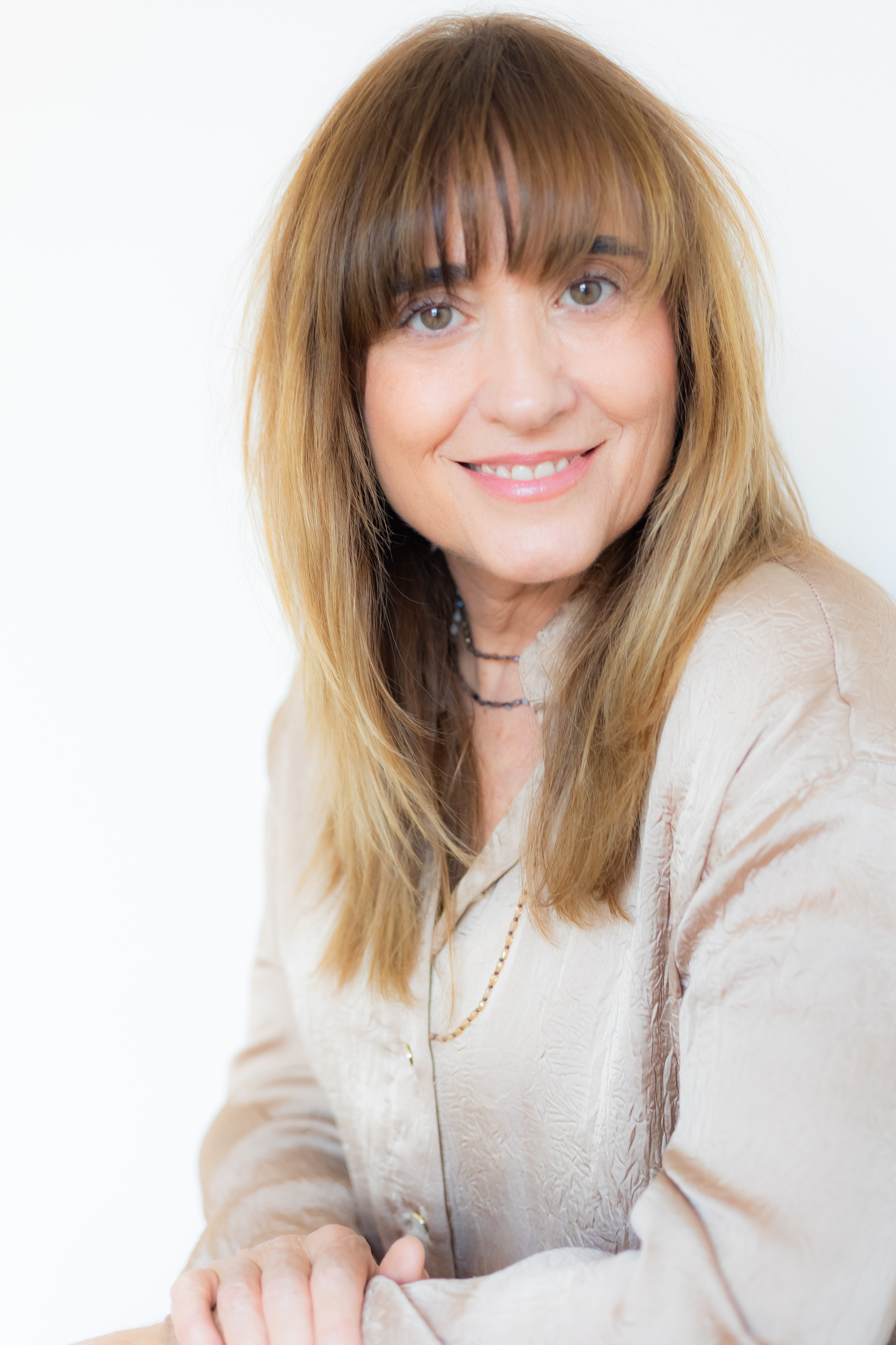 Persona con el pelo largo rubio sonriendo y una chaqueta color beige