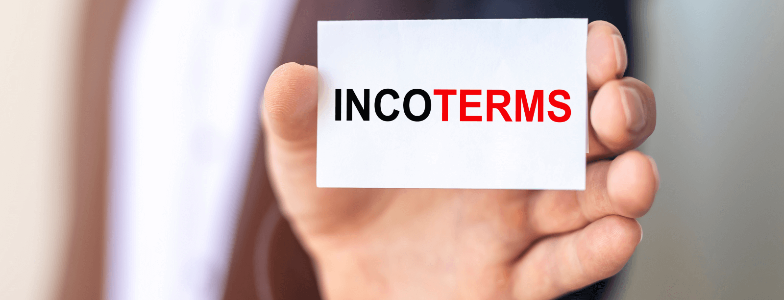Una mano sujetando una tarjeta con el texto INCOTERMS