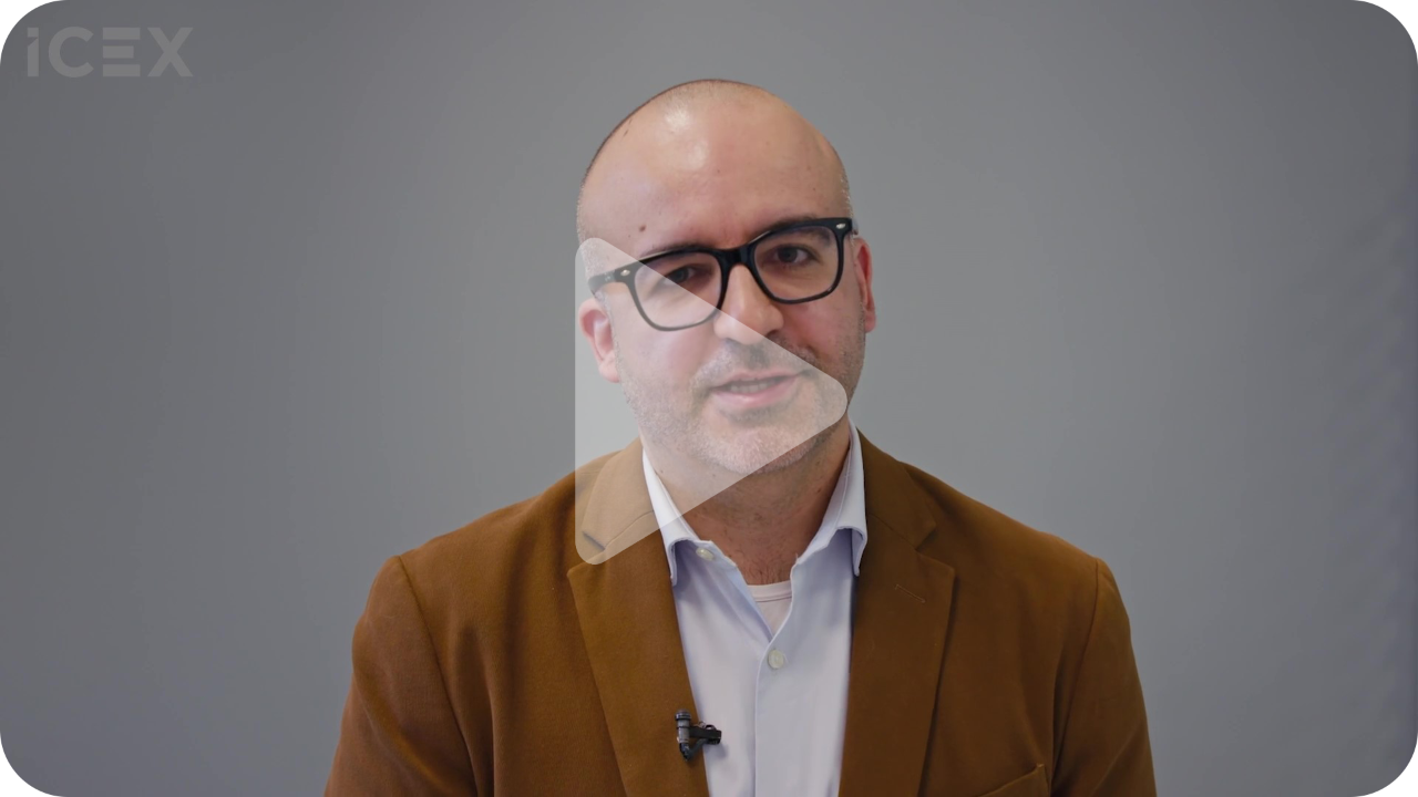 Primer plano de hombre con americana marrón y gafas sobre fondo gris
