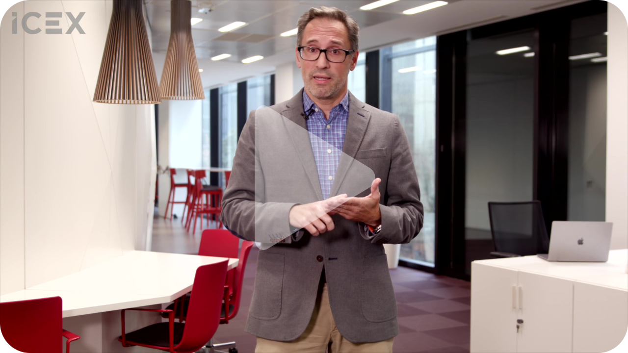 Plano americano de hombre con gafas y chaqueta gris en una oficina