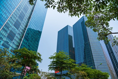 Closeup of top modern high-rise building in Dao Tan street, Hanoi, Vietnam. Mirroring of concrete skyscrapers on blue sky in shiny glass windows.