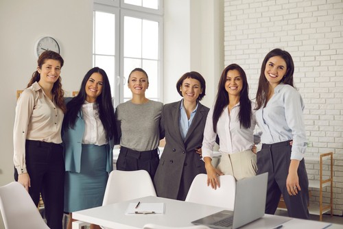 grupo de mujeres sonrientes junto a mesa de trabajo