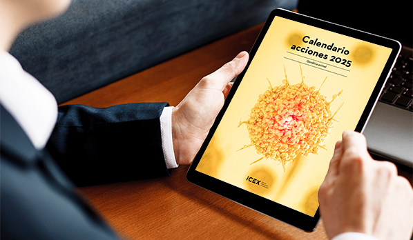Un hombre con traje azul sujeta una tablet en la que se visualiza la portada del calendario de actividades para el sector de genética animal.