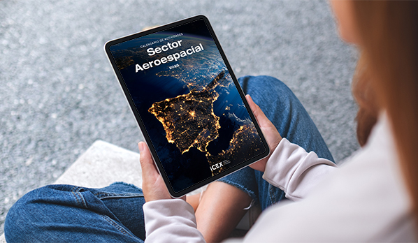 Una mujer con jersey blanco visualiza en una tablet la portada del calendario de ICEX para el sector aeroespacial