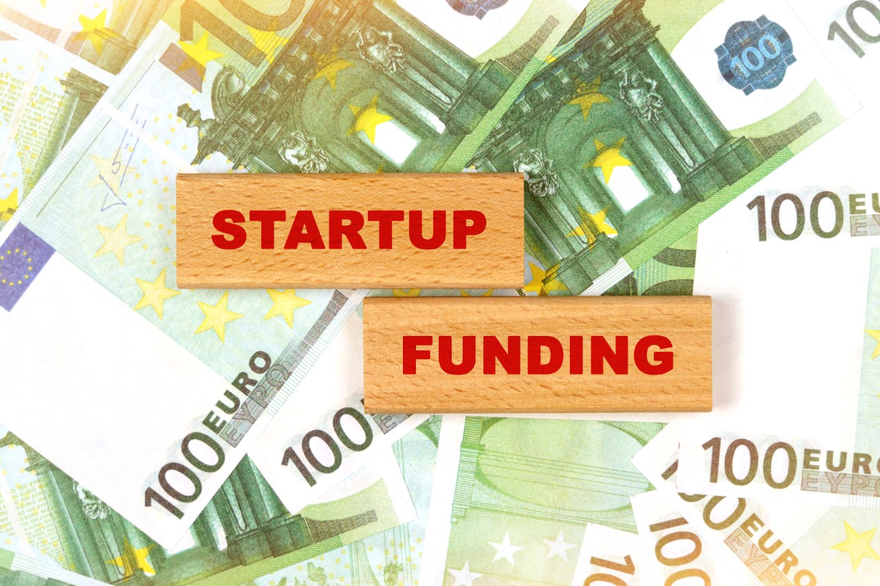 Carteles con las palabras startup y funding puestos encima de unos billetes de 100 euros
