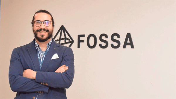 Vicente González, cofundador de Fossa Systems, posa sonriente al lado del logo de su empresa