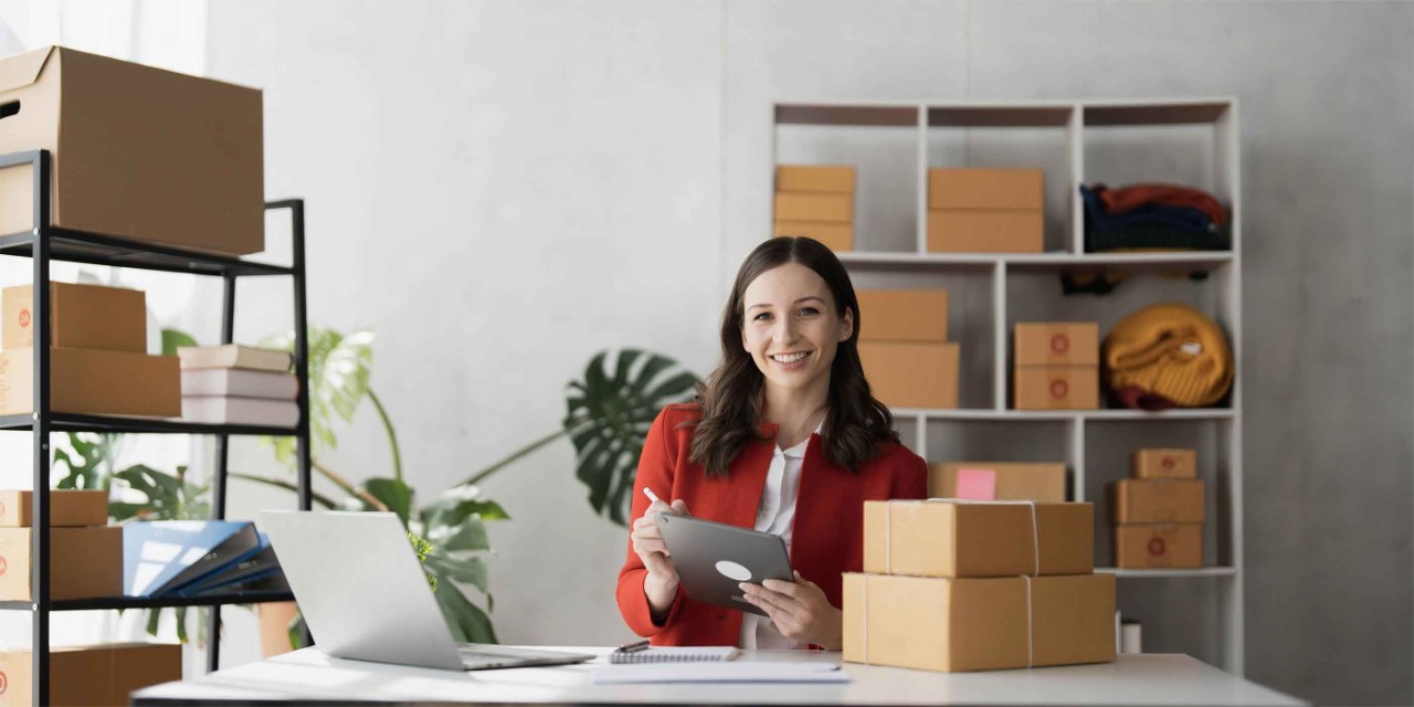 Retratar la sonrisa de la mujer de negocios y usar la información de verificación de tablet en la caja de envío de paquetes antes de enviarla al cliente.