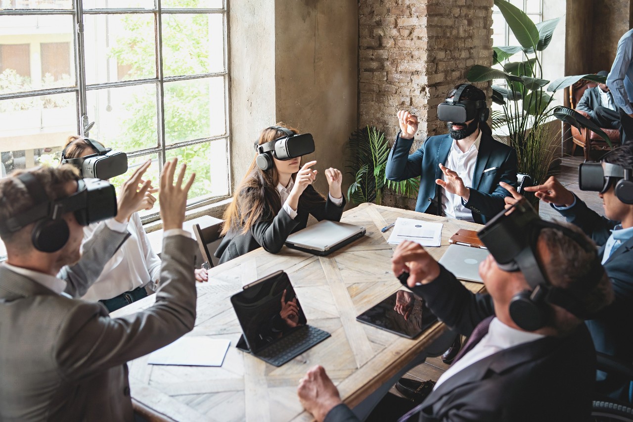 Varios ejecutivos hombres y mujeres se reúnen en una mesa mientras miran con sus gafas de realidad virtual