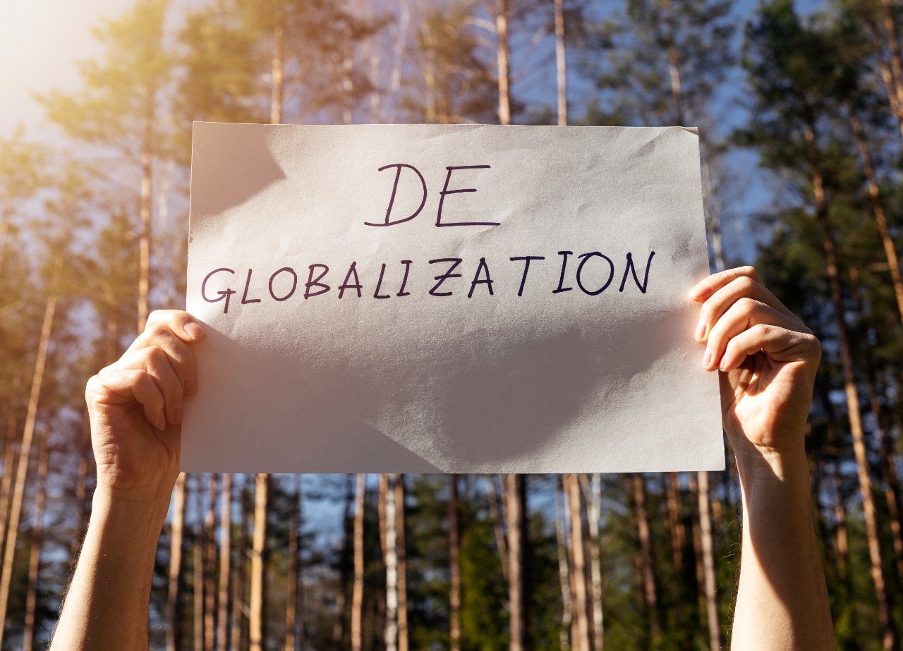 Una persona en un bosque sujeta una hoja de papel en la que pone "Deglobalization"