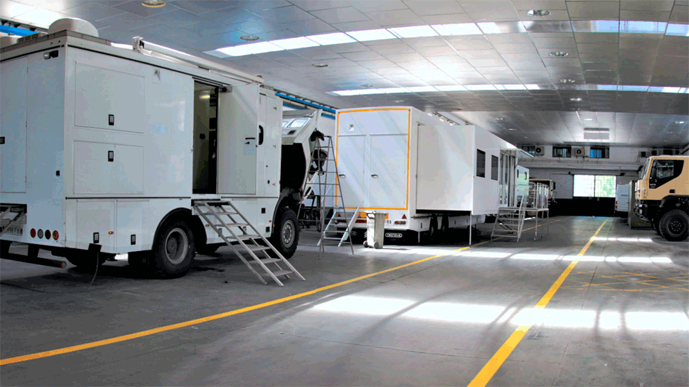 Una flota de camiones blancos se encuentra estacionada dentro de una nave de logística