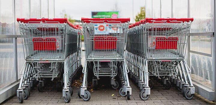 Tres filas de carritos de la compra con el mango rojo. Sirven para comprar bienes de consumo en Reino Unido