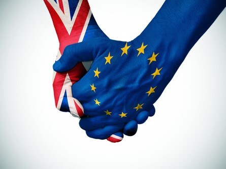 Dos manos estrechándose. La de la derecha está pintada con la bandera de la UE, y la de la izquierda con la de Reino Unido