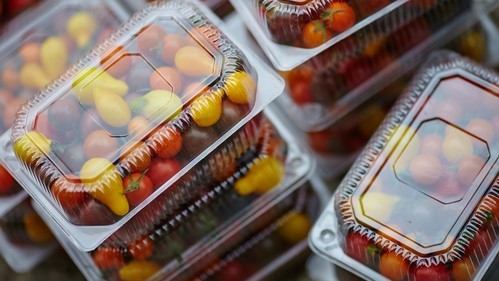 Envases de plástico transparentes con tomates y otras verduras de pequeño tamaño en su interior