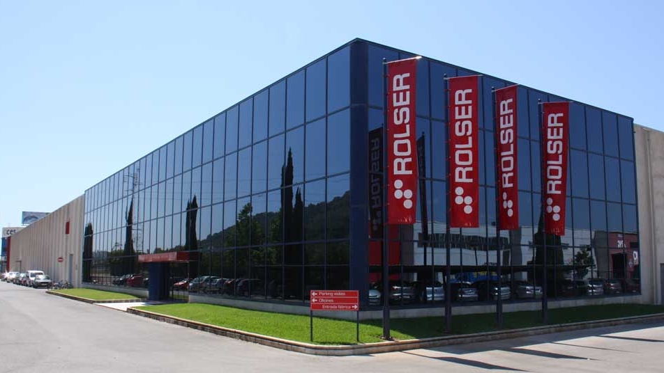 Edificio hecho con paneles de cristal de la compañía Rolser con el logo colgado y alrededores