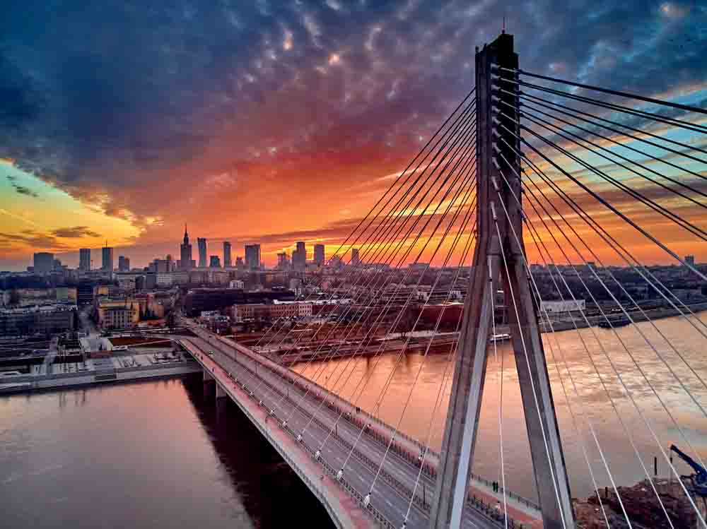 Paisaje de un atardecer con un puente y edificios al fondo de la imagen