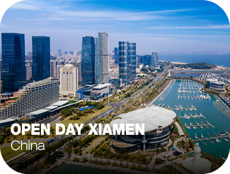 Open Day Xiamen. China. A la izquierda una fila de rascacielos, una carretera con jardines en los laterales y un gran pabellón. A la derecha, un río con muelles.